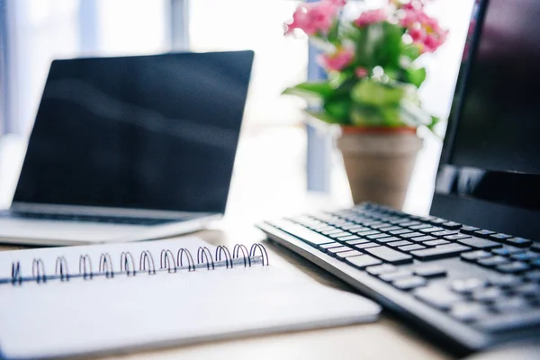 Primer plano de libro de texto vacío, portátil, flores en maceta, ordenador, teclado de la computadora y el ratón de la computadora en la mesa - foto de stock