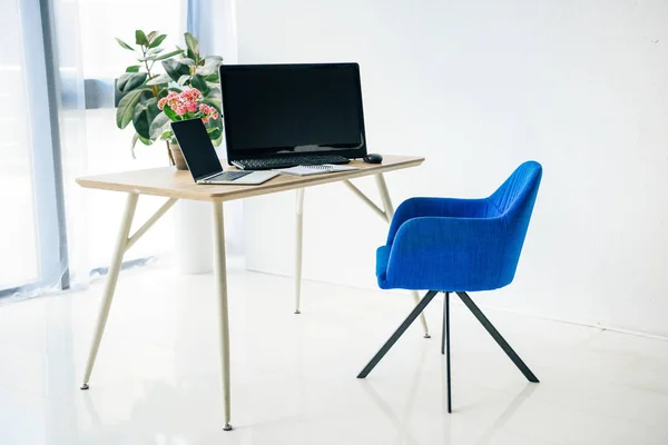 Intérieur de la chambre avec chaise, table, plantes en pot, ordinateur portable, ordinateur, souris d'ordinateur et clavier d'ordinateur — Photo de stock