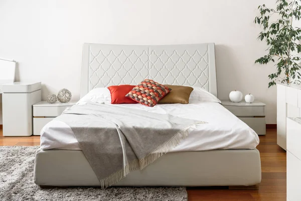 Interior de dormitorio de luz moderna con almohadas de colores en la cama blanca - foto de stock