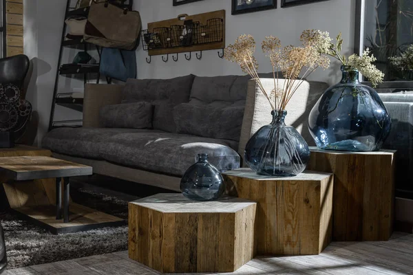 Interior of modern retro styled living room with grey sofa and vases on wooden shelves — Stock Photo