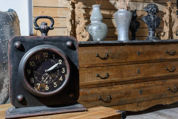 Old vintage clock on wooden table in modern retro styled living room — Stock Photo