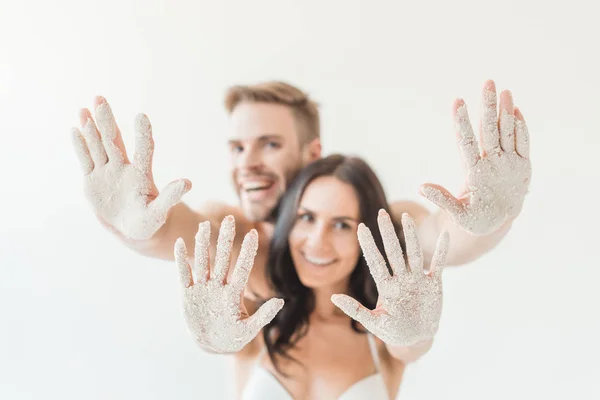 Foco seletivo de casal alegre mostrando mãos na areia, isolado no branco, isolado no branco — Fotografia de Stock