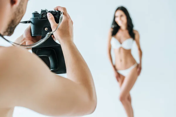 Enfoque selectivo del hombre tomando la foto de la mujer hermosa en bikini, aislado en blanco - foto de stock