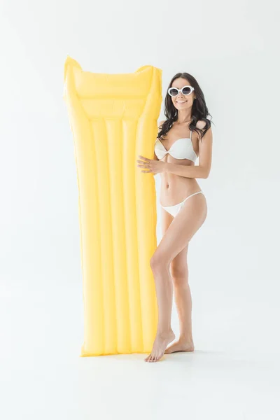 Attraktive Frau im Bikini posiert mit gelber aufblasbarer Matratze, isoliert auf weiß — Stockfoto