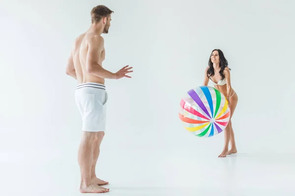 Bella coppia in costume da bagno giocare con la palla da spiaggia, isolato su bianco — Foto stock