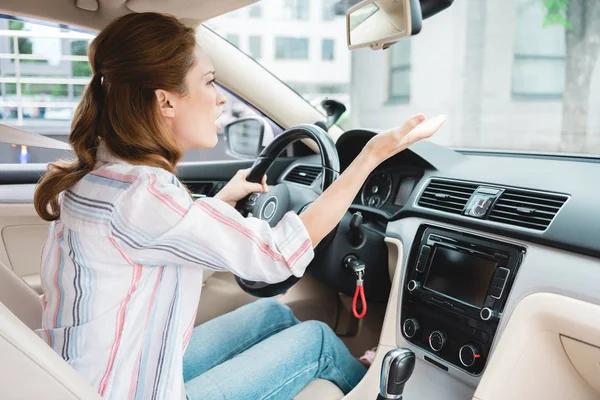 Vista lateral de la mujer emocional gesto mientras conduce el coche - foto de stock