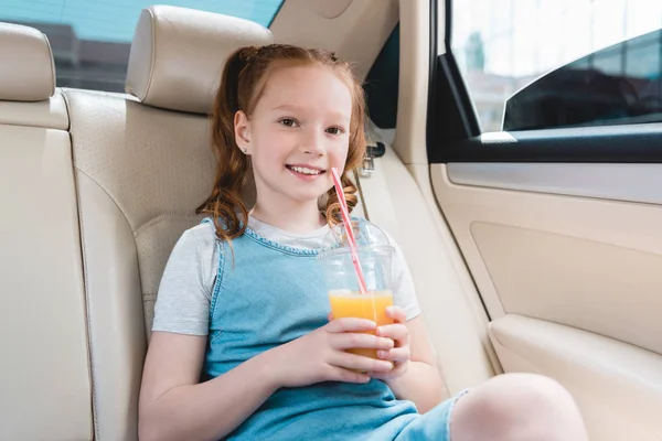 Retrato de niño alegre con jugo sentado en el coche - foto de stock