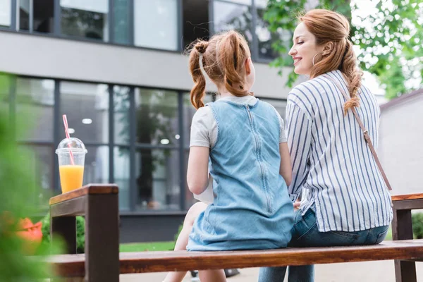 Back view of mother and daughter resting on bench on street — Stock Photo