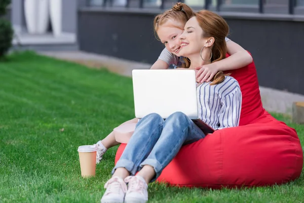 Mãe e filha com laptop descansando na cadeira saco juntos — Fotografia de Stock