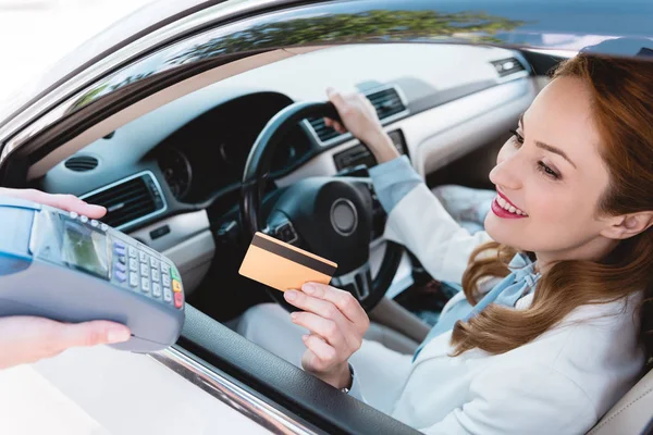 Lächelnde Geschäftsfrau im Auto, die mit Kreditkarte bezahlt — Stock Photo