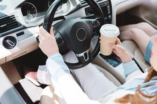 Partial view of businesswoman with coffee to go driving car with daughter near by — Stock Photo