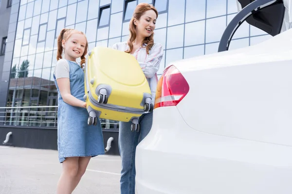 Fröhliche Familie packt Gepäck in Auto auf der Straße — Stockfoto