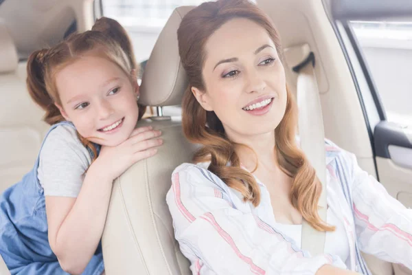 Portrait d'une mère souriante conduisant une voiture avec sa fille sur le siège des passagers — Photo de stock