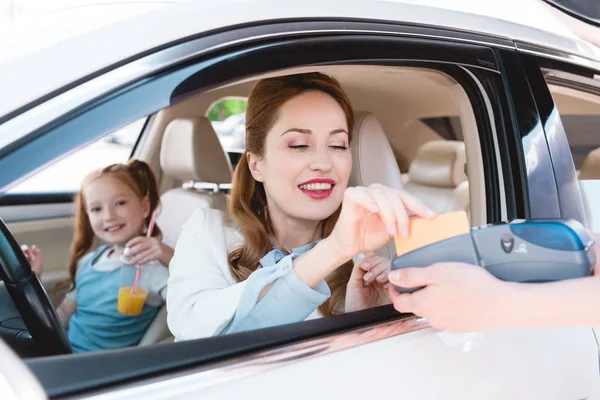 Sonriente mujer de negocios pagando con tarjeta de crédito para llevar orden en coche - foto de stock