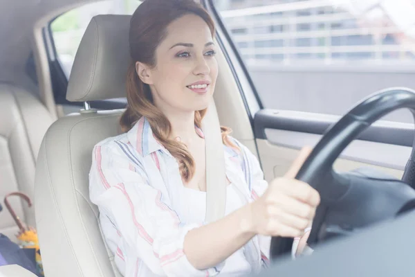 Porträt einer lächelnden Frau mit den Händen am Steuer — Stockfoto