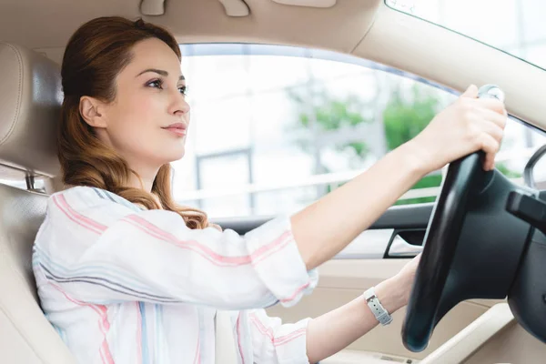 Vista lateral de mujer atractiva conduciendo coche solo - foto de stock