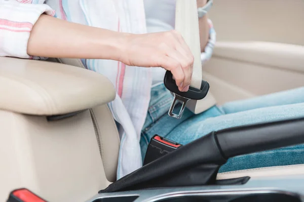Partial view of woman fastening seat belt in car — Stock Photo