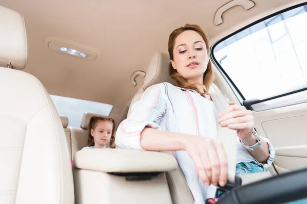 Blick in den niedrigen Winkel: Frau schnallt sich während Autofahrt mit Tochter auf Beifahrersitz an — Stockfoto