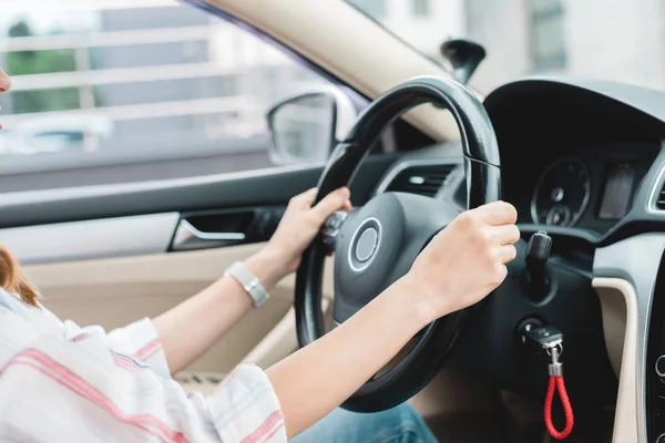 Vista parcial de la mujer con las manos en el volante de conducción del coche — Stock Photo