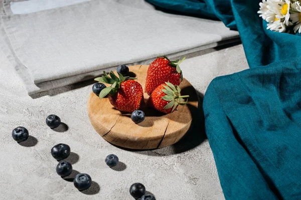 Fresas y arándanos en bruto sobre tabla de madera - foto de stock