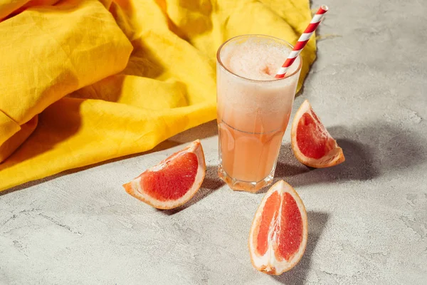 Glass with fresh grapefruit juice on table with citrus pieces — Stock Photo