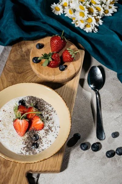 Graines de chia dans un bol avec des fraises et des bleuets sur une planche de bois — Photo de stock