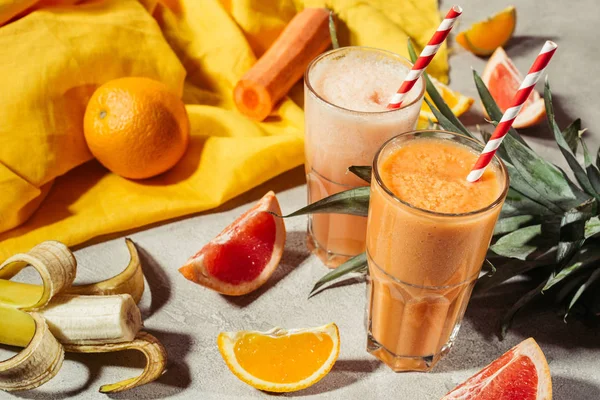 Óculos com suco de frutas tropicais e pedaços de frutas na mesa cinza — Fotografia de Stock