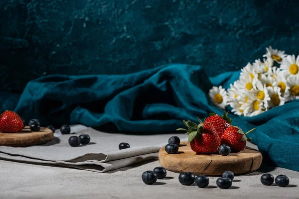 Strawberries and blueberries with tablecloth and daisies on table — Stock Photo
