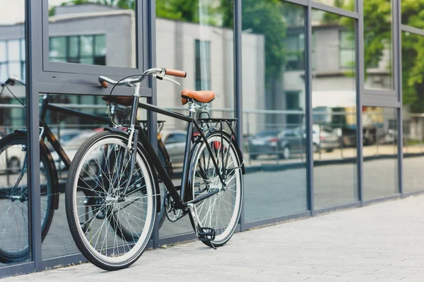 Comfortable bicycle reflected in modern building on empty street — Stock Photo