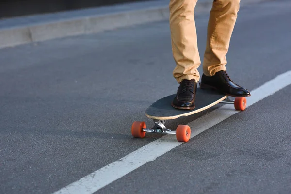 Cropped shot of young man standing on skateboard on street — Stock Photo