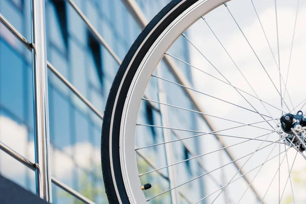 Крупный план велосипедного колеса с шинами за пределами современного здания, выборочная фокусировка — стоковое фото