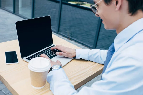 Cropped shot of smiling young businessman using laptop with blank screen — Stock Photo