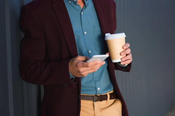 Обрізаний знімок молодого чоловіка, що тримає паперову чашку та використовує смартфон — стокове фото