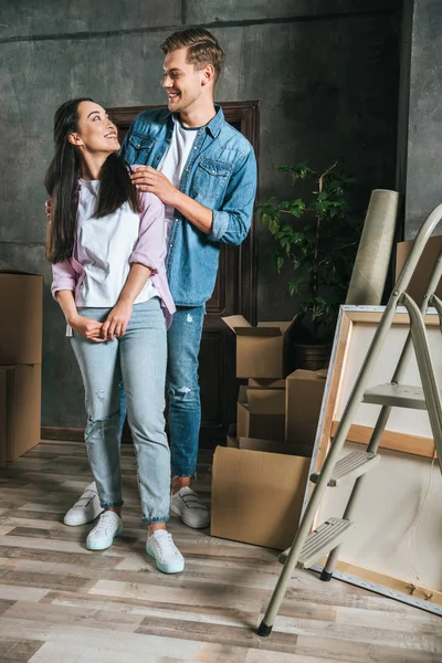Sonriente joven pareja con cajas moviéndose en nuevo hogar - foto de stock