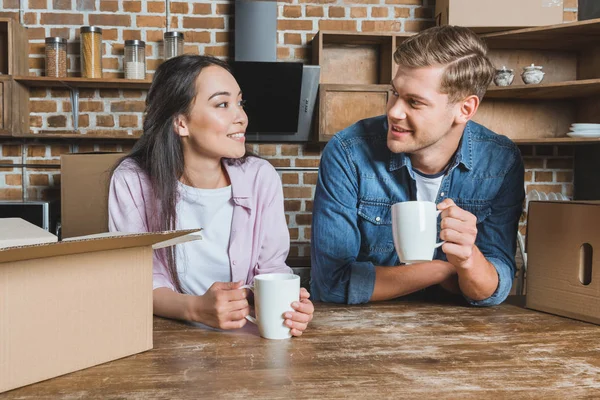 Happy young couple drinking coffee at kitchen of new home — Stock Photo