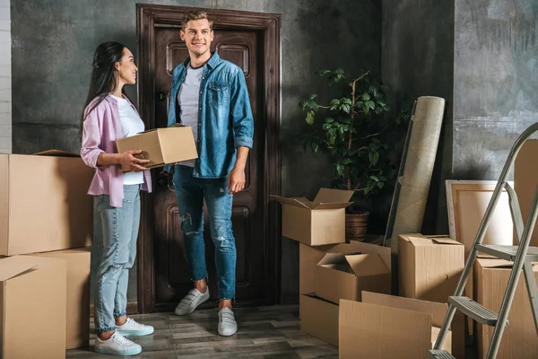 Heureux jeune couple avec beaucoup de boîtes déménageant dans une nouvelle maison — Photo de stock