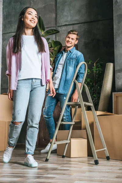 Красива молода пара з коробками і драбинами переїжджає в новий будинок — стокове фото
