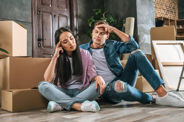 Young couple sitting on floor after argument while moving into new home — Stock Photo