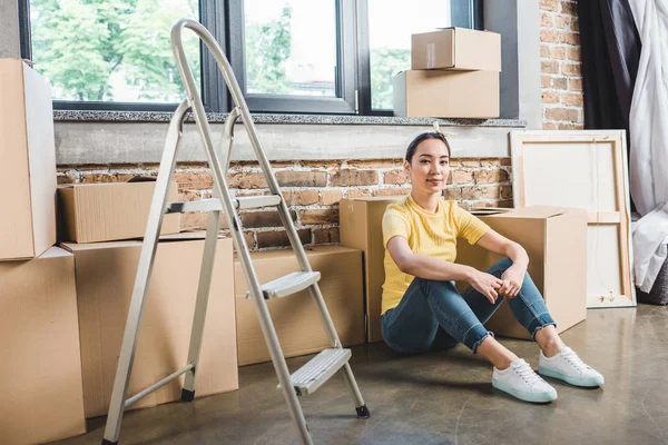 Junge Asiatin nach Umzug auf dem Boden sitzend umgeben — Stockfoto