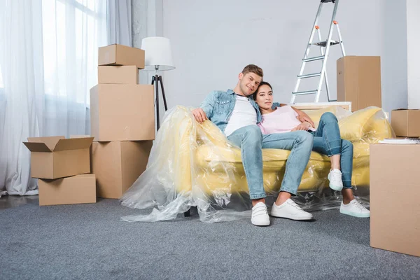 Glückliches junges Paar entspannt auf dem Sofa beim Einzug ins neue Zuhause — Stockfoto