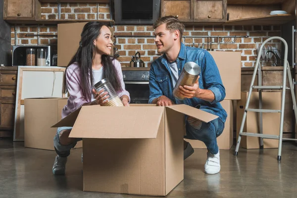 Interracial young couple unpacking boxes on kitchen while moving into new home — Stock Photo
