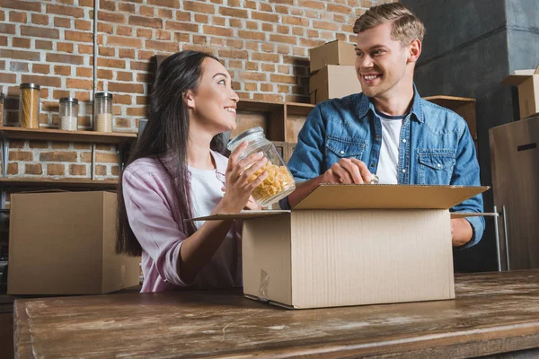 Glückliches junges Paar beim Auspacken von Kisten in der Küche beim Einzug ins neue Zuhause — Stockfoto