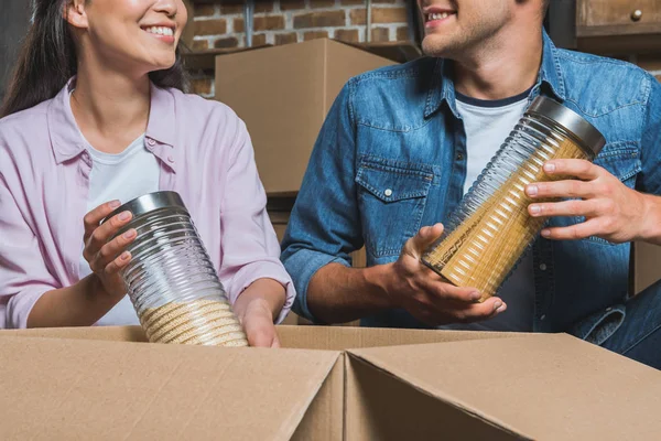 Recortado disparo de joven pareja sacando frascos de cajas mientras se muda a nuevo hogar - foto de stock