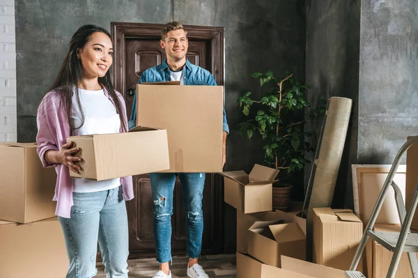 Hermosa pareja joven con cajas mudándose a un nuevo hogar - foto de stock