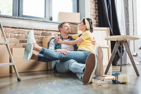 Amour jeune couple assis sur le sol ensemble tout en déménageant dans une nouvelle maison — Photo de stock