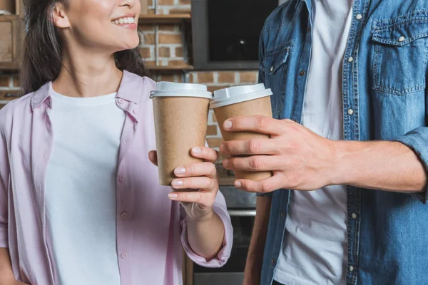 Cropped shot of couple clinking paper cups of coffee at kitchen — Stock Photo
