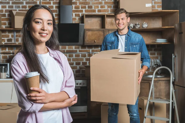 Belo jovem casal com caixas e café para ir se mudar para uma nova casa — Fotografia de Stock