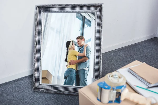 Mirror reflection of beautiful couple embracing after moving into new home — Stock Photo
