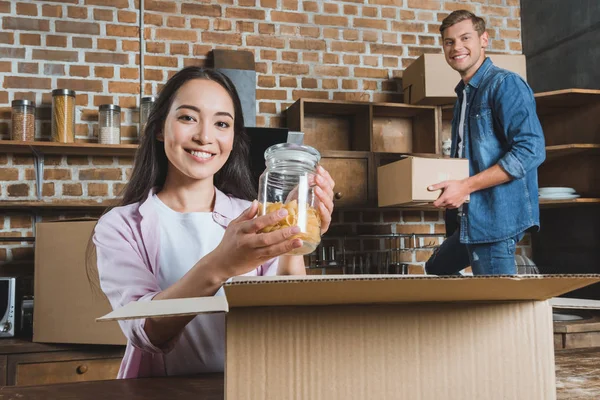 Beaux jeunes boîtes de déballage de couple pendant le déménagement dans une nouvelle maison — Photo de stock