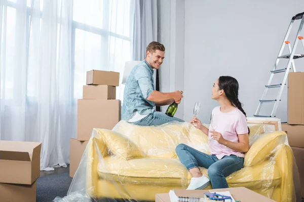 Sonriente joven pareja con champán celebrando después de mudarse a un nuevo hogar - foto de stock